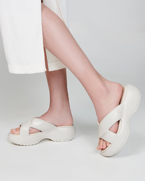 Model's legs in a pair of beige Free Rise platform slides