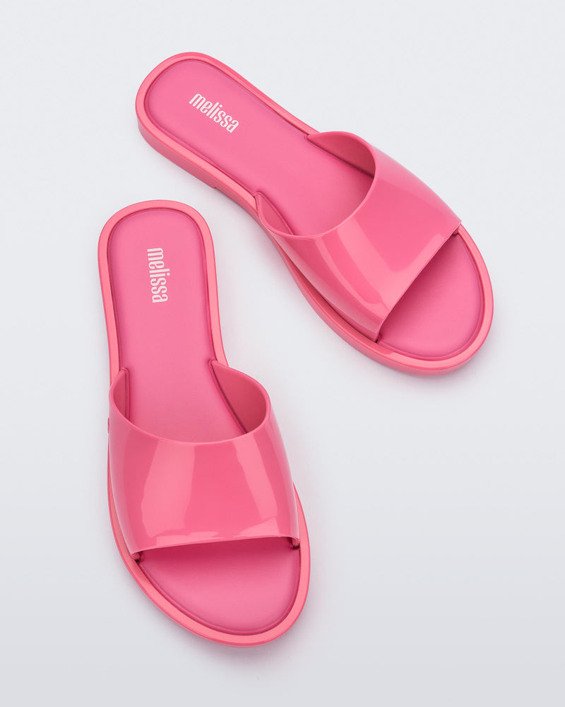 An angled top view of a pair of pink tortoiseshell Melissa Miranda slides