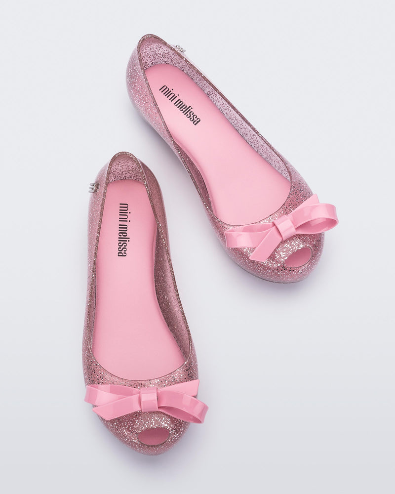 Top view of a Glitter Pink Mini Melissa Ultragirl Bow Glitter flat with a pink glitter base and pink bow