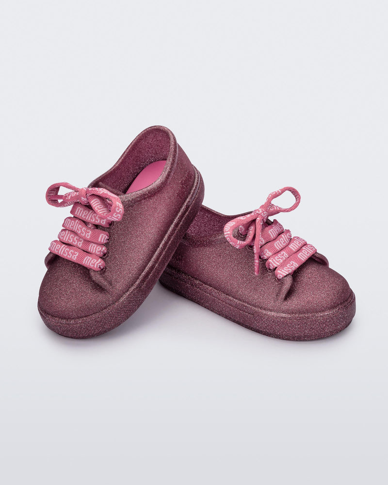 Angled view of a pair of glitter pink baby Hip M Lover sneakers with laces
