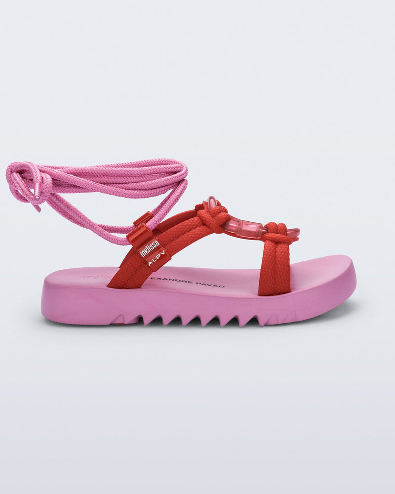 Side view of an pink sole, red upper, and pink ankle strap Kirk + Alexandre Pavao sandal