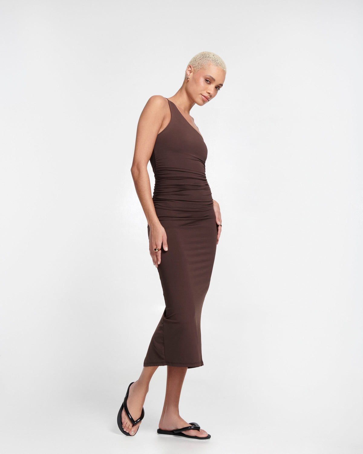 Model in a brown dress wearing a pair of black Flip Flop Airflow sandals with white bottoms.