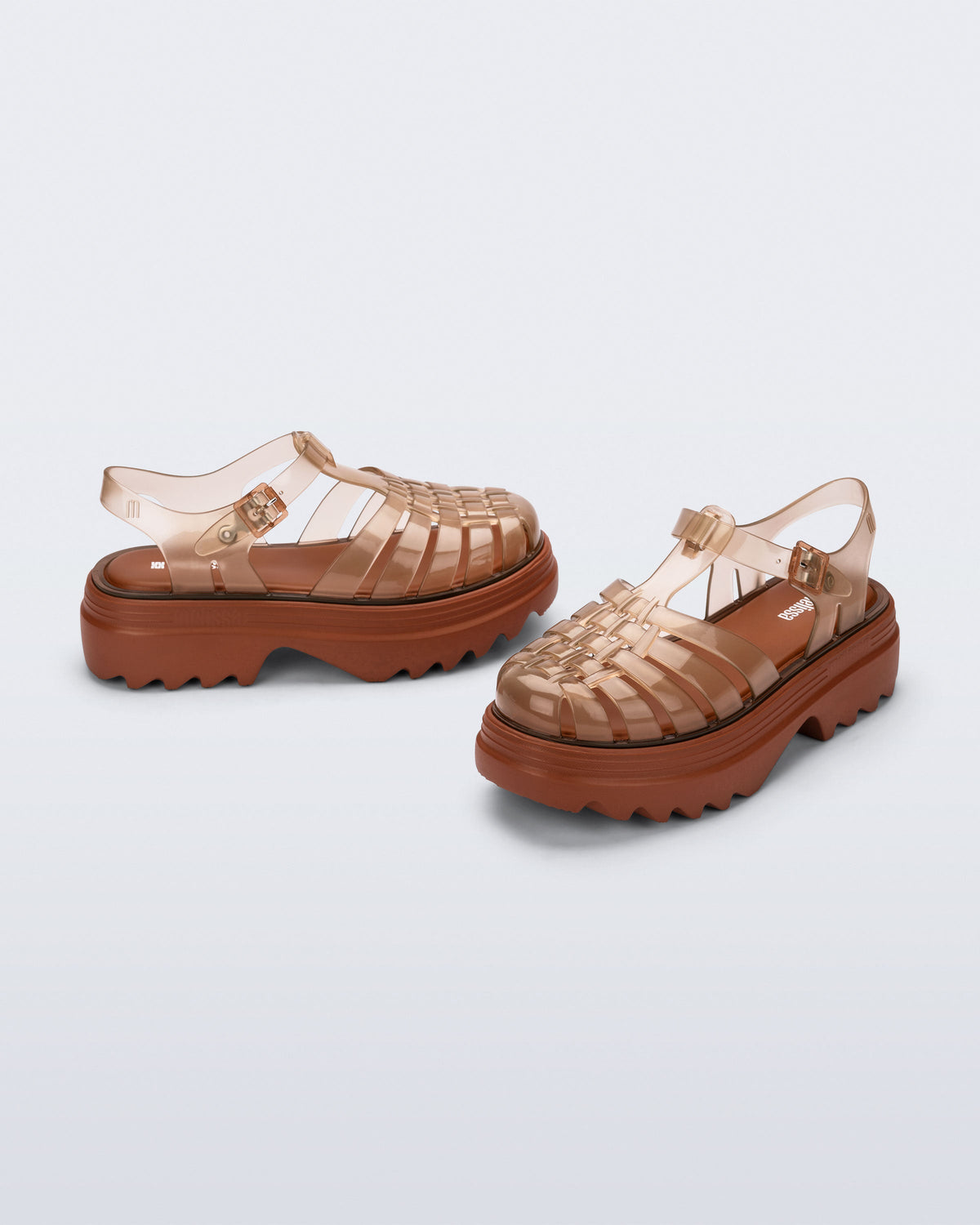 Side and front angled view of a pair of transparent brown Possession Platform II fisherman sandals