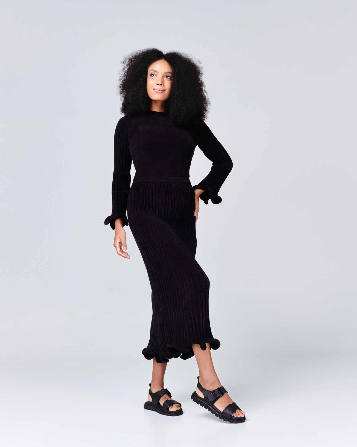 Model in a black dress wearing a pair of black Connection Papete sandals.