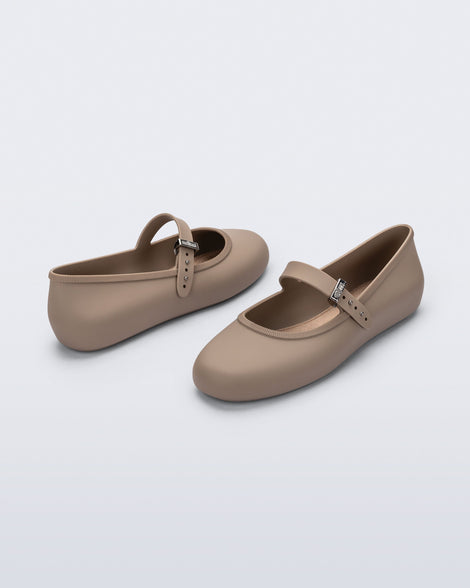 Side and front angled view of a pair of dark beige Soft Ballerina flats with top buckle strap