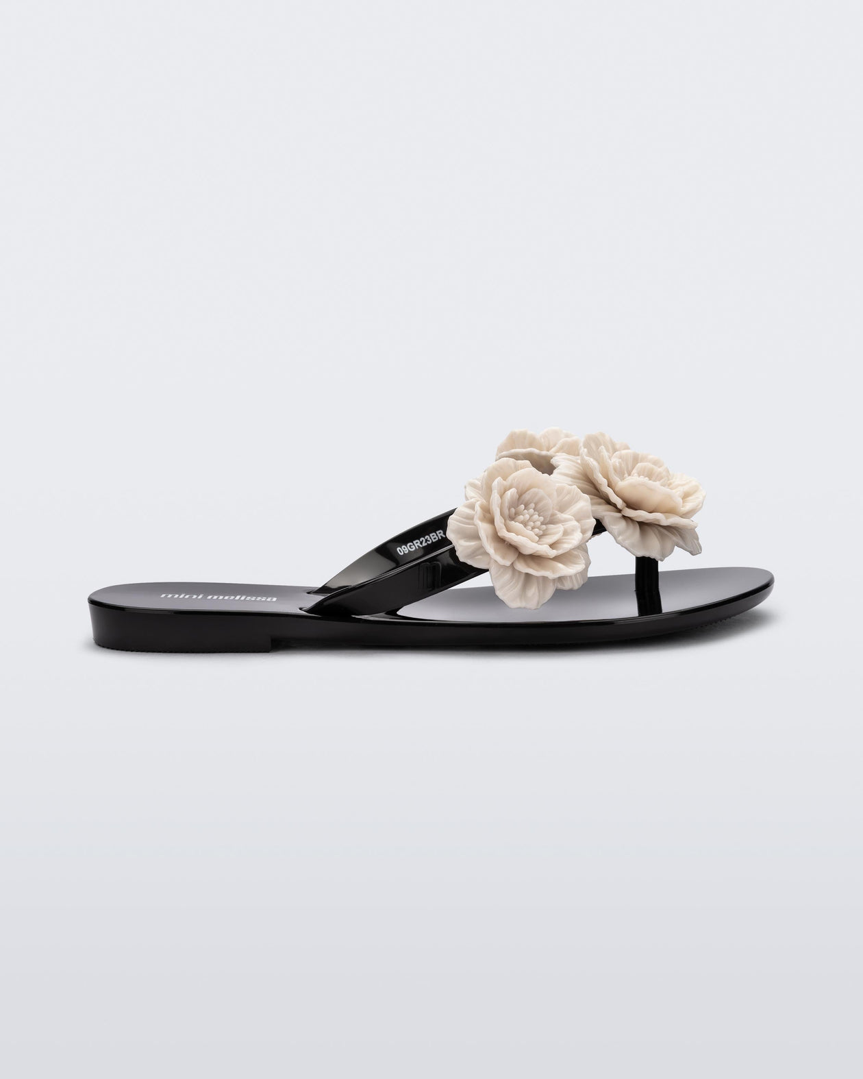 Side view of a black Harmonic Springtime kids flip flop with three beige flowers.