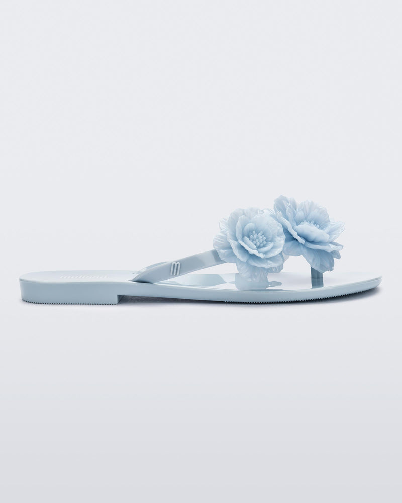 Side view of a pair of blue Harmonic Springtime women's flip flop with 3 blue flowers.