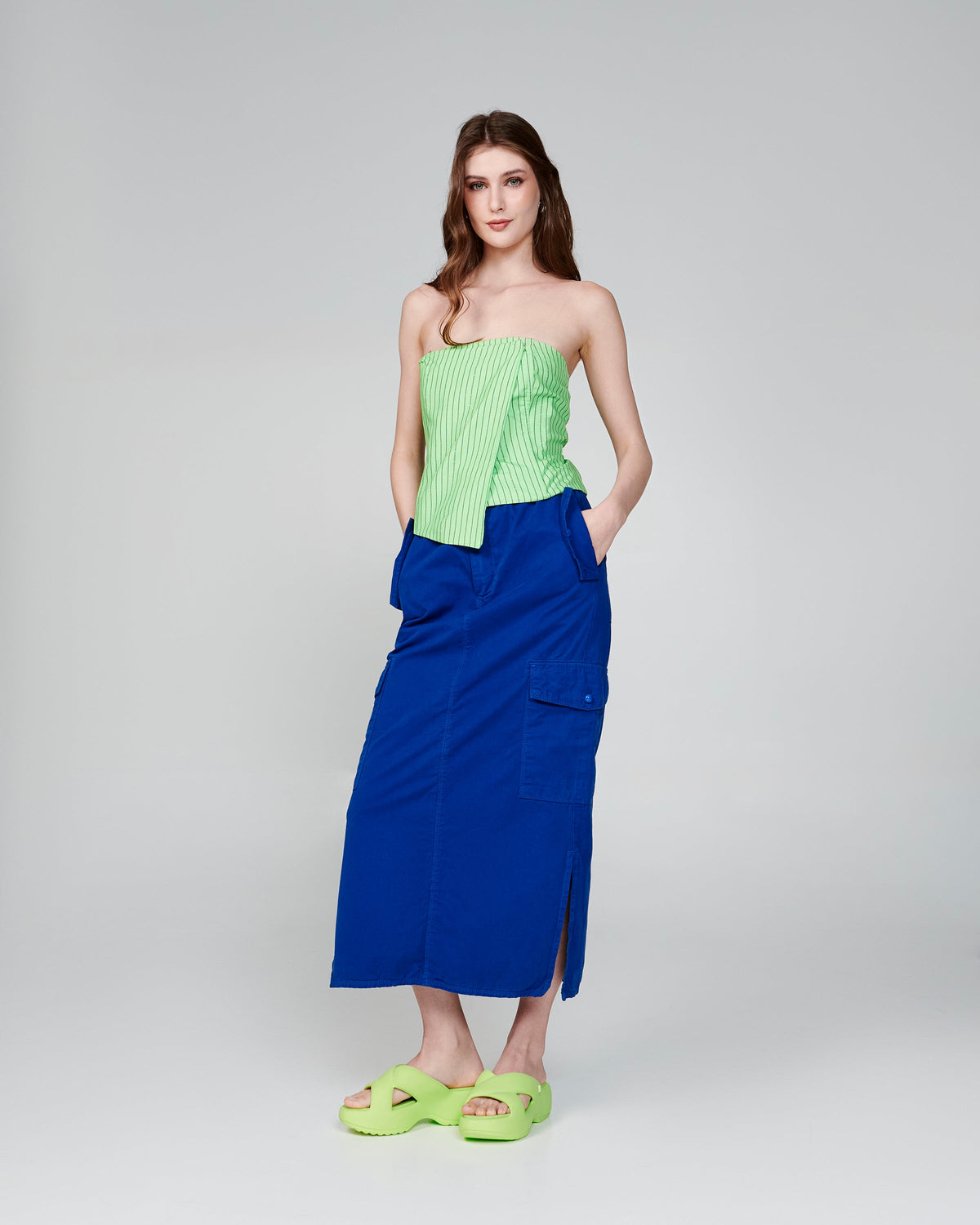 Model in a blue skirt and green top wearing a pair of green Free Rise platform slides
