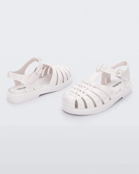 An angled front and back view of a pair of white Mini Melissa Possession sandals with several straps and a white base.