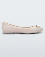 Side view of a light beige Melissa flat with a beige bow detail with gold accents on the toe