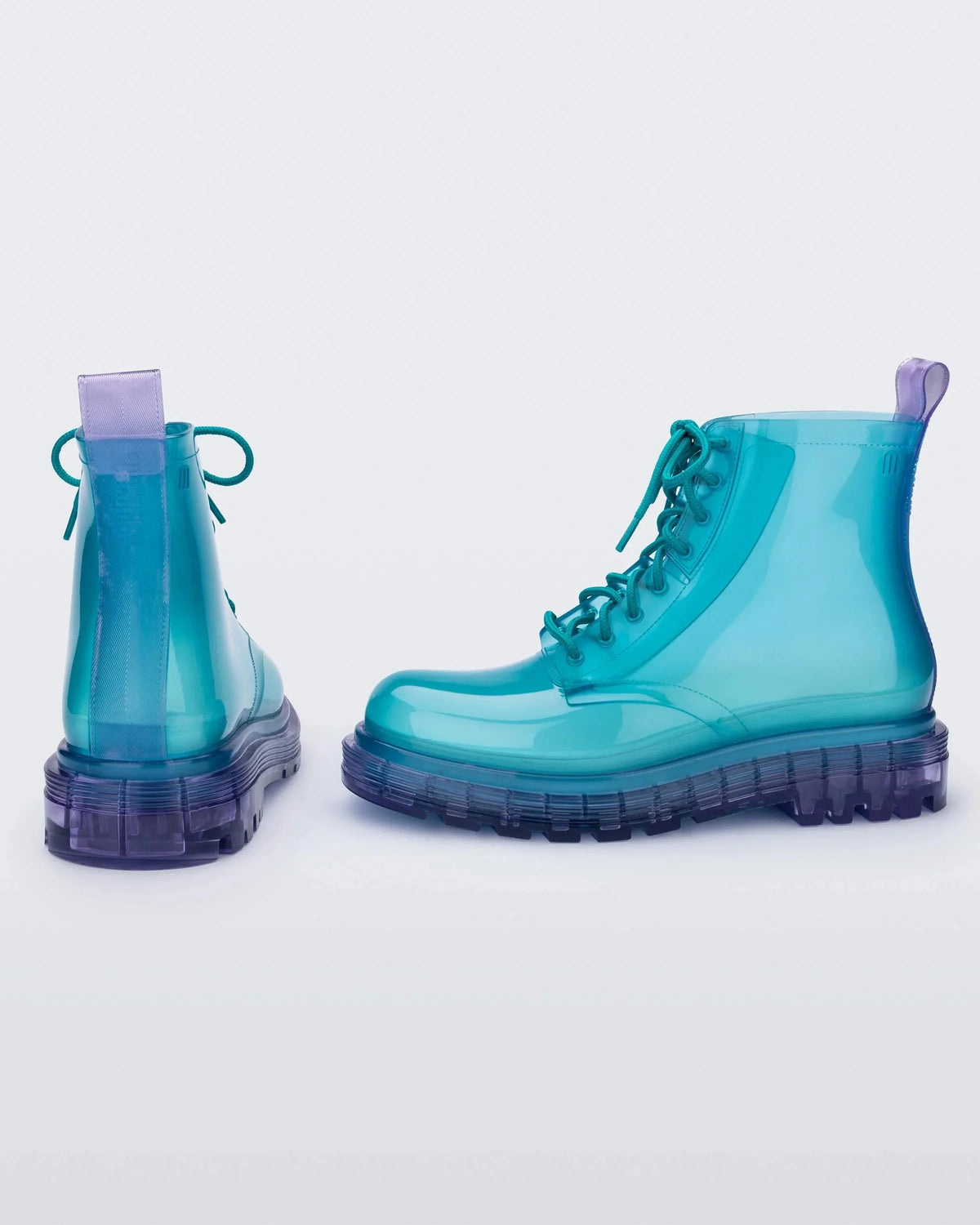 A back and side view of a pair of clear lilac/blue Melissa Coturno boots with a transparent blue base, laces and a lilac sole.