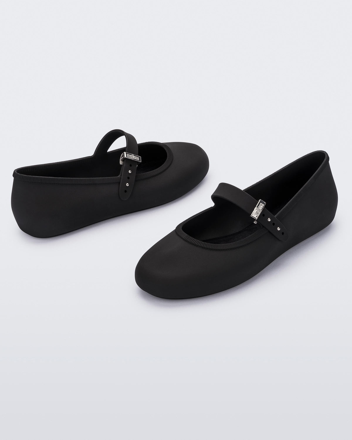 Angled view of a pair of black Soft adult flats with strap and silver buckle
