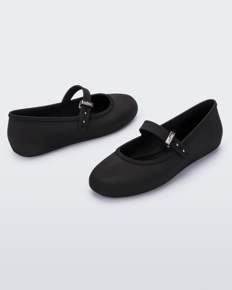 Angled view of a pair of black Soft adult flats with strap and silver buckle