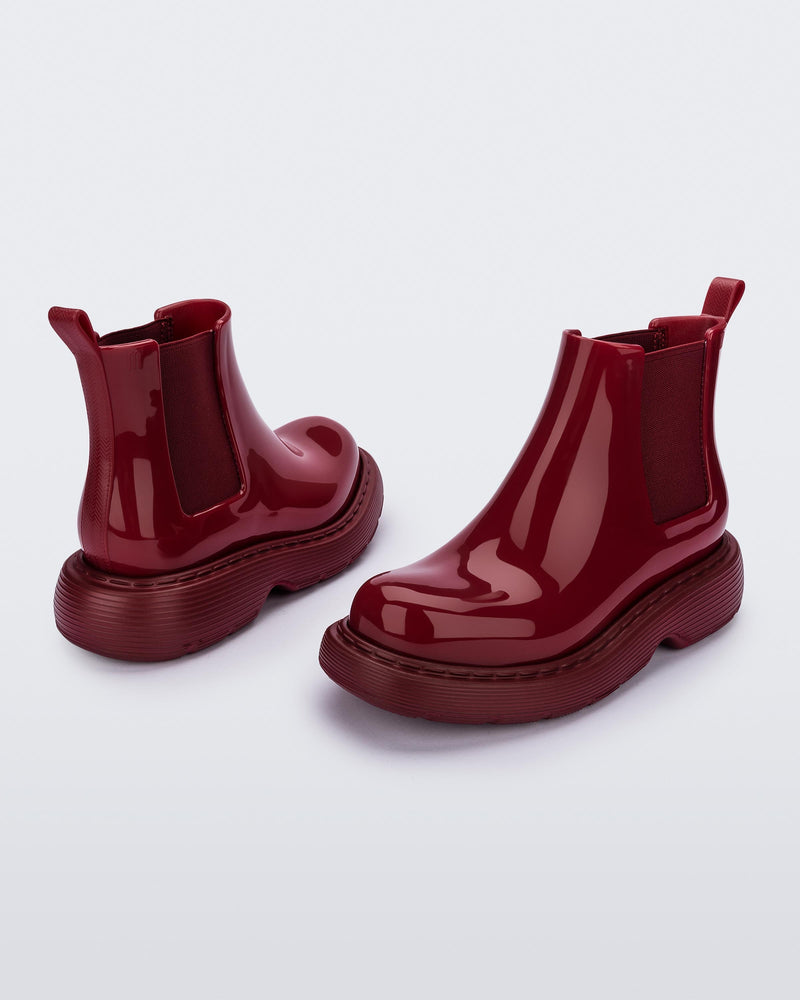 Angled view of a pair of Melissa Step slip on ankle boots in Red with stretch side detail and lugg sole