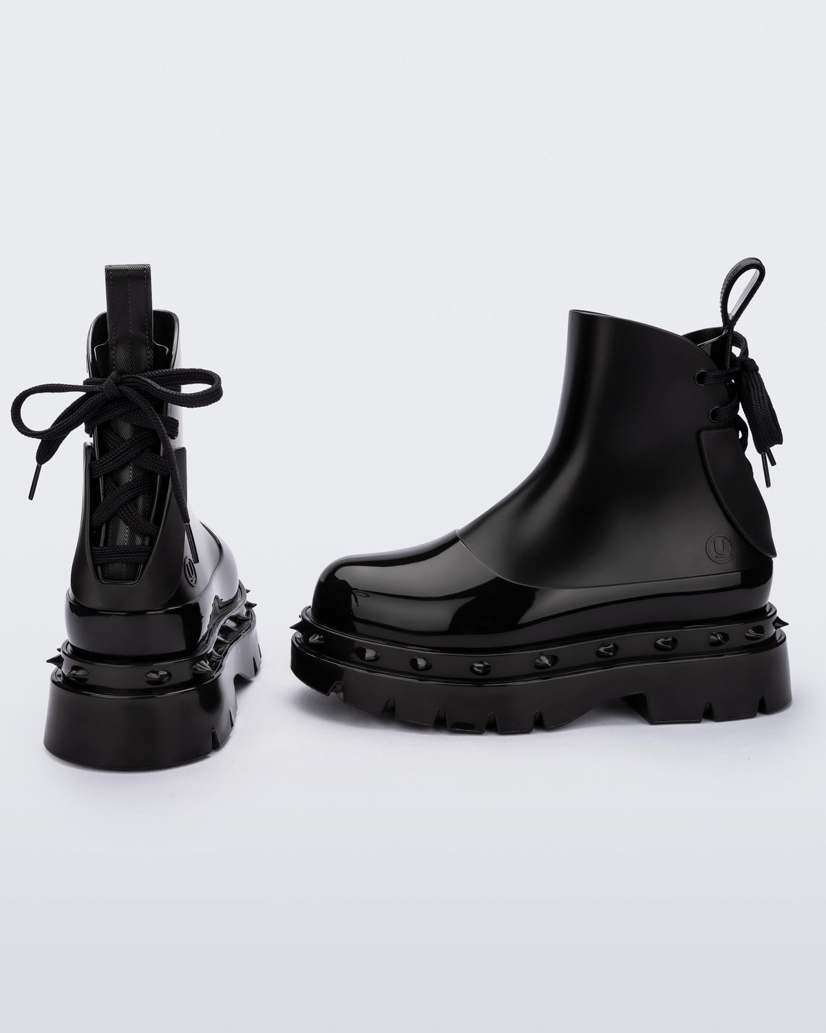 A side and back view of a pair of black Melissa Spikes Boots with spike details around the sole and laces in the back.