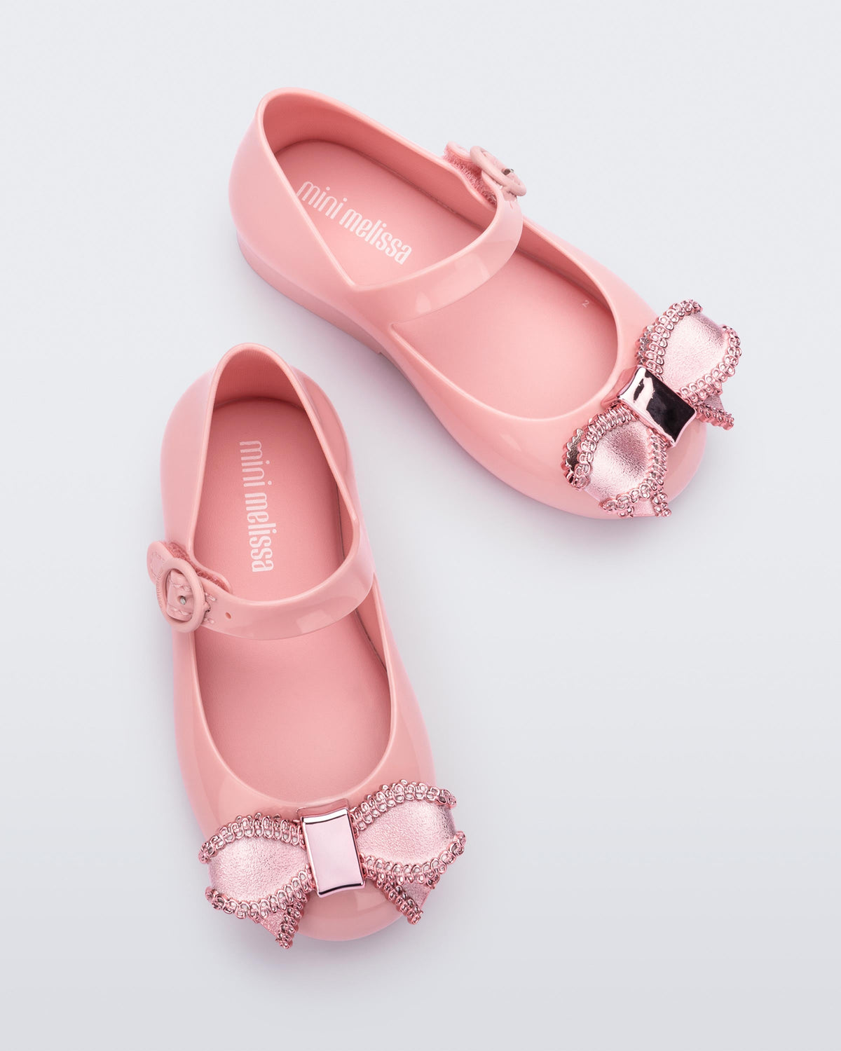 Top view of a pair of pink Mini Melissa Sweet Love baby mary jane flats with a metallic pink bow.