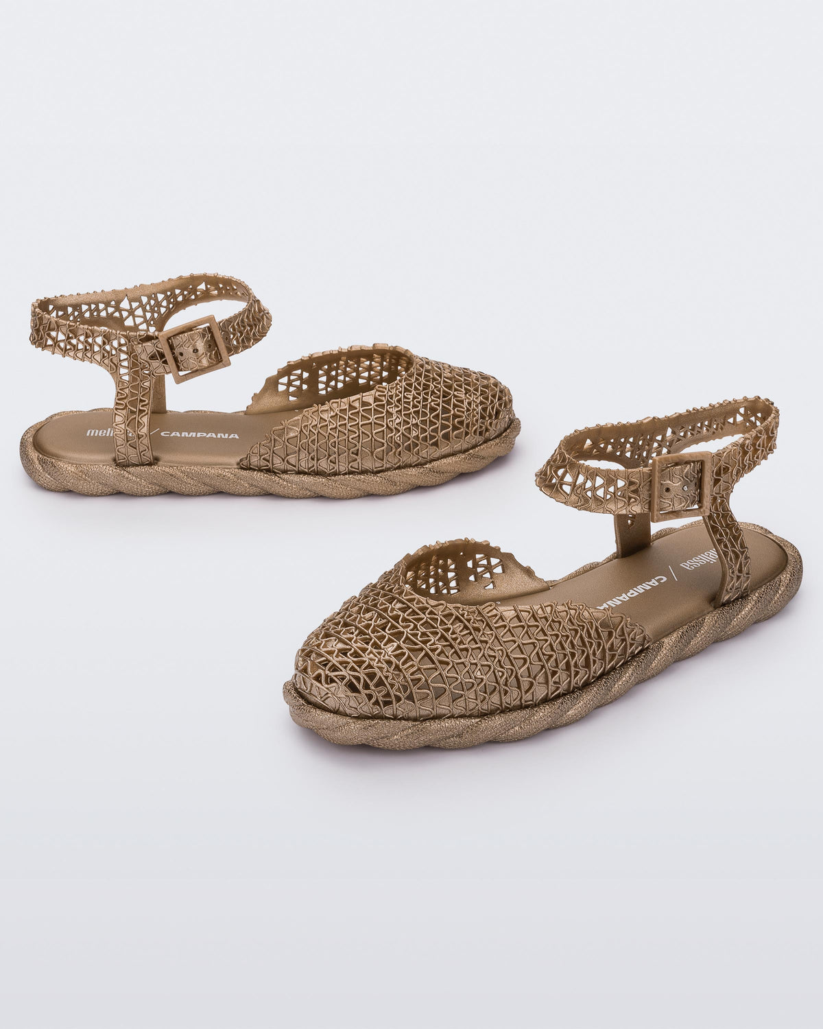 Side and angled view of a pair of gold Melissa Papel Espadrille Campana sandals with braided sole detail and ankle strap