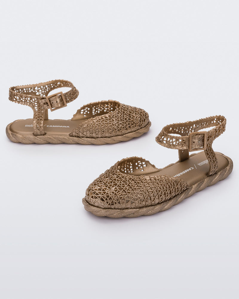 Side and angled view of a pair of gold Melissa Papel Espadrille Campana sandals with braided sole detail and ankle strap