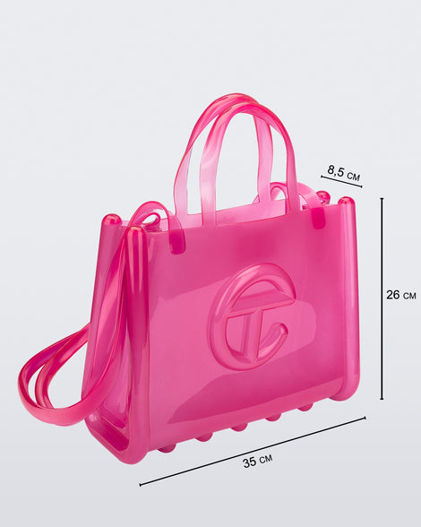 Angled view of a pink medium Melissa Jelly Shopper bag + Telfar bag with a handle and straps. Dimensions 35 cm length, 8.5 cm width, 26 cm height
