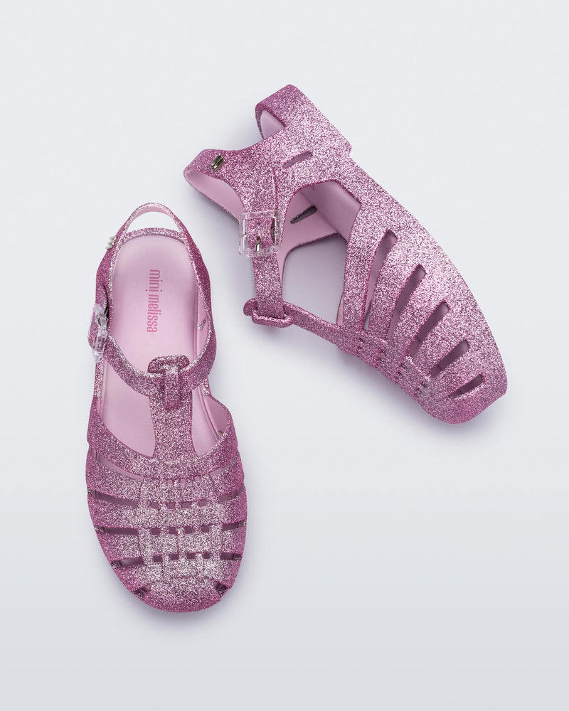 Top and side view of a pair of glitter pink kids Possession sandals.