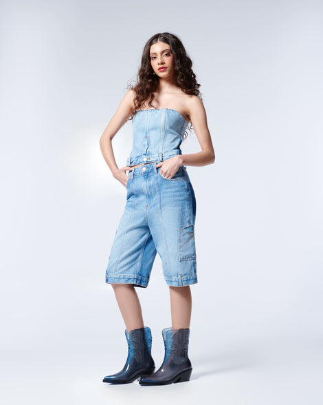 Model in a jean shirt ans long jean shorts wearing a pair of transparent blue Texas boots