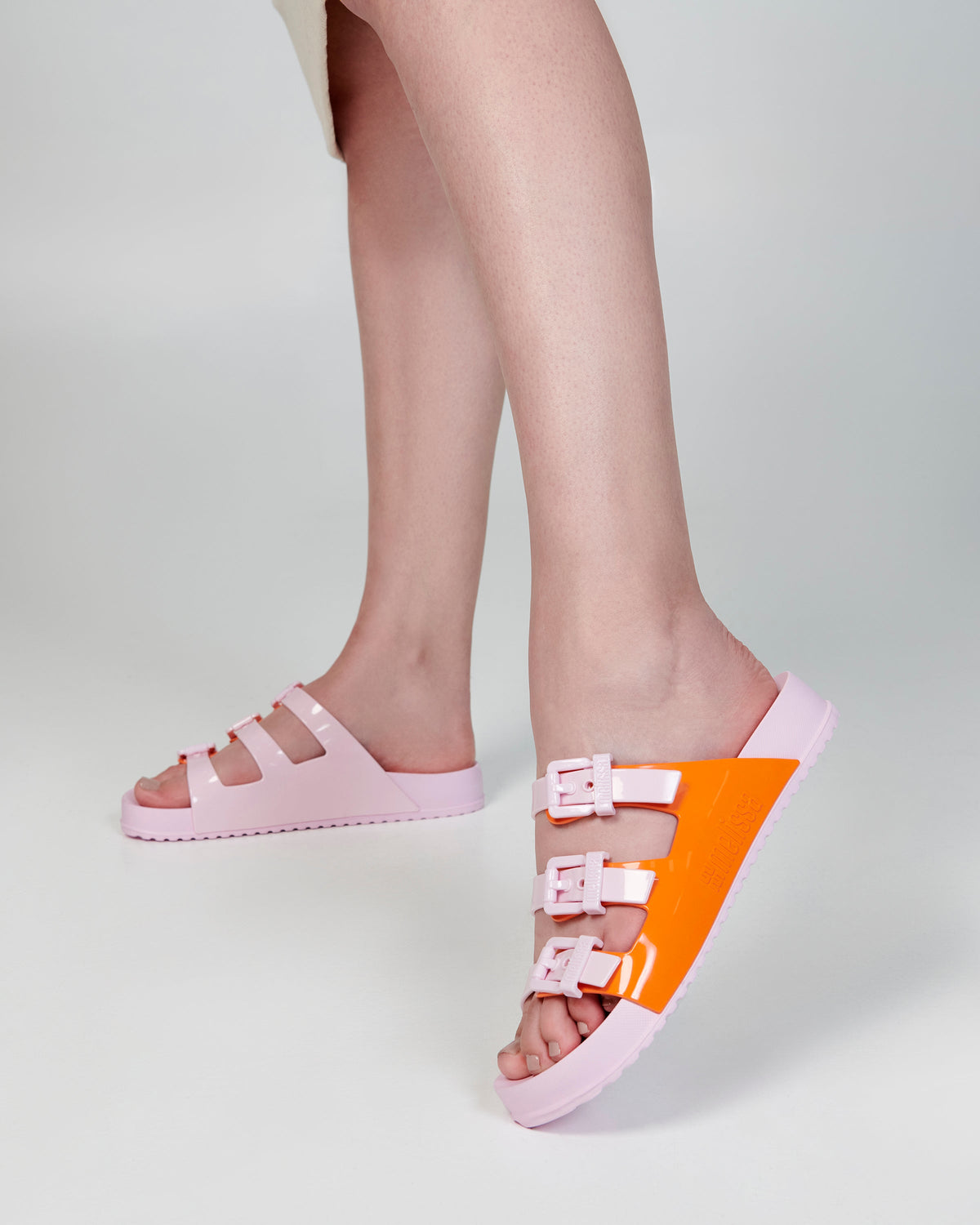Model's legs wearing a pair of pink and orange Cozy Stripes slides