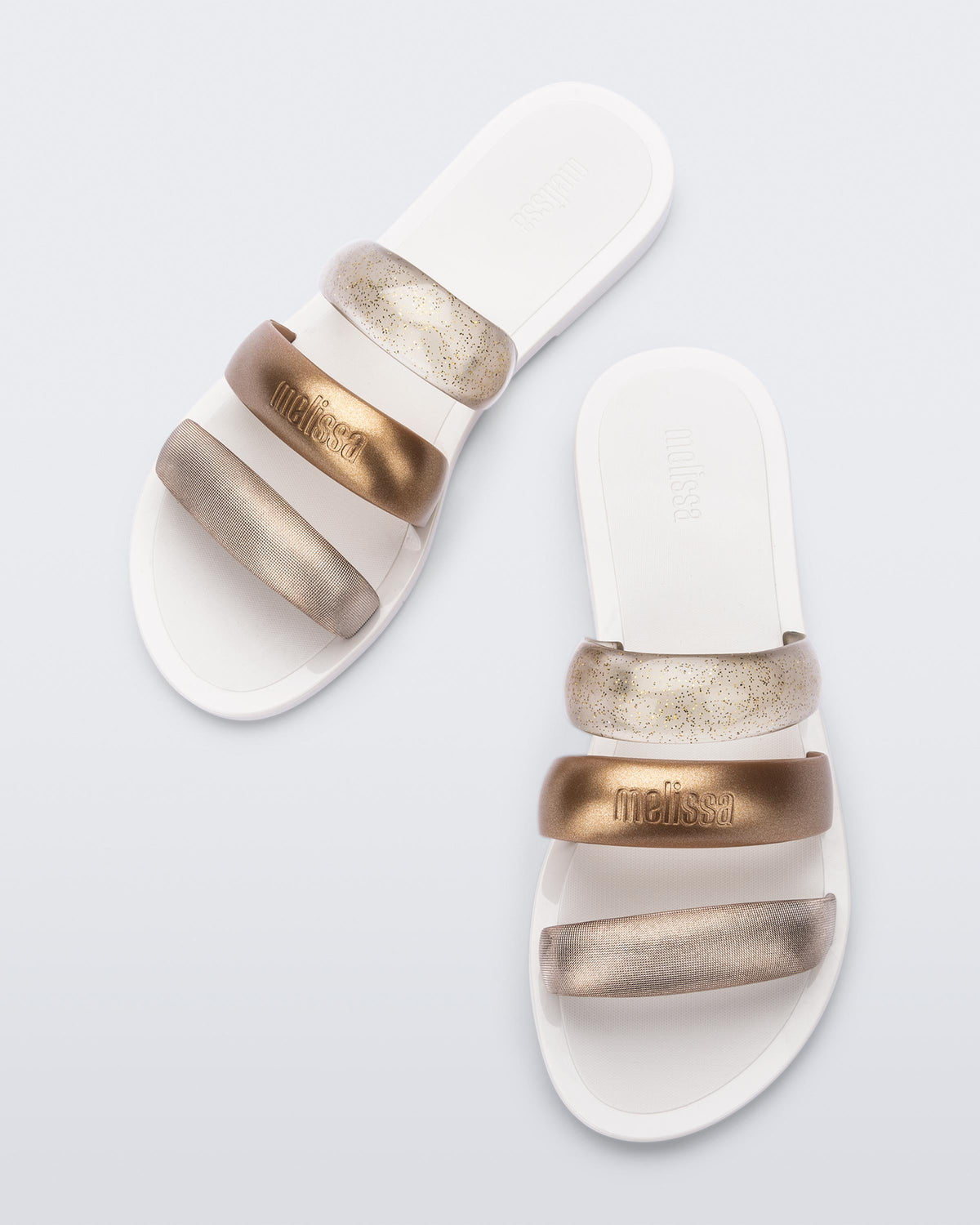 Top view of a pair of white Eclipse Slides with bronze straps.