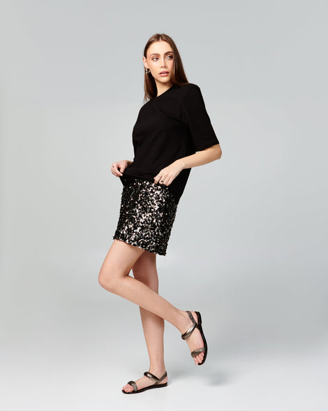 Model in black shirt and sparkly skirt wearing a pair of black Eclipse Sandals with silver straps.