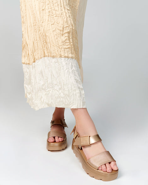 Model's legs wearing a pair of gold Kick Off Sandals