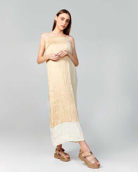 Model in a beige dress wearing a pair of gold Kick Off Sandals