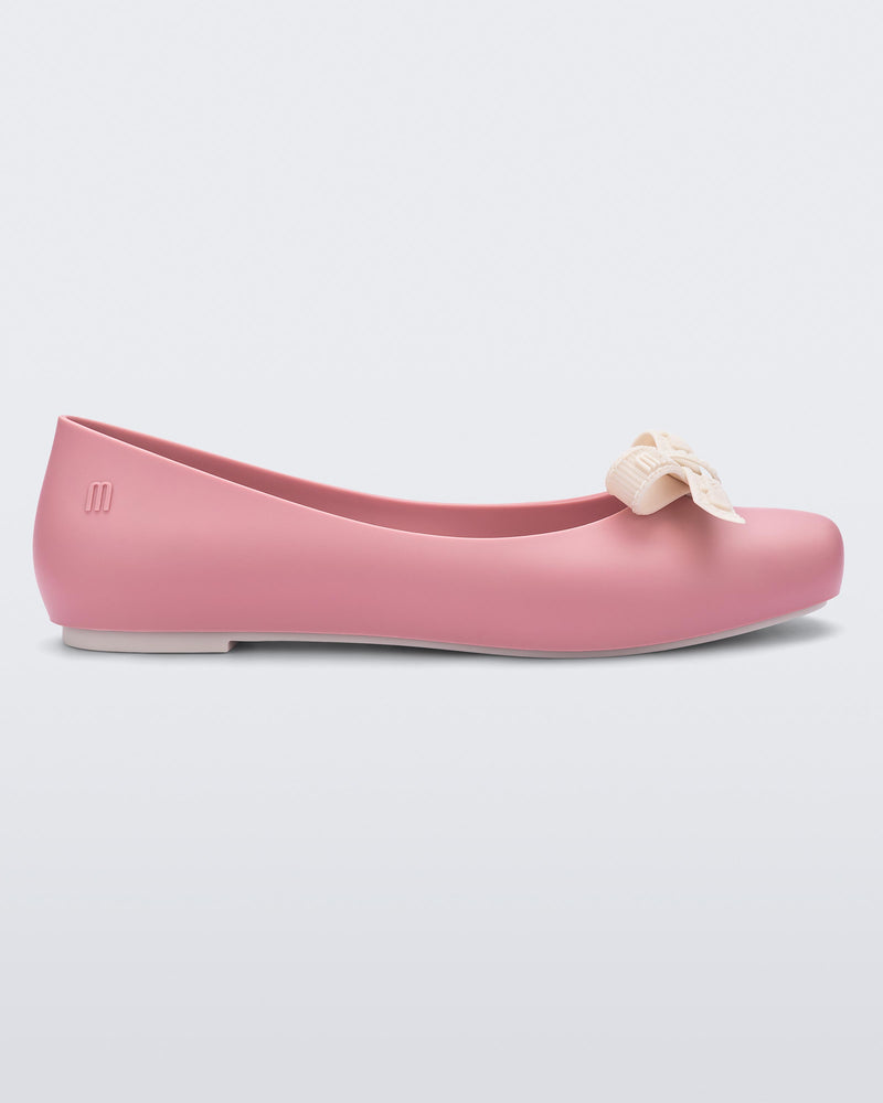 Side view of Melissa Aura flat in Pink with a beige bow on a light gray background