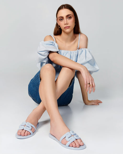 Model in jean shorts wearing a pair of light blue M Slides.