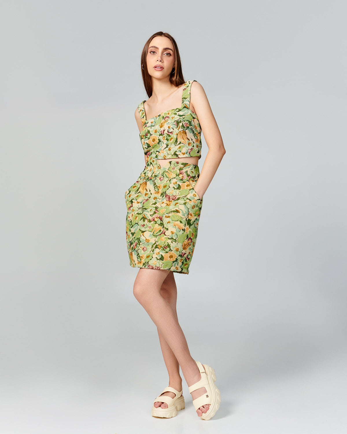 Model in a multi color green outfit wearing a pair of beige Ella Move platform sandals.