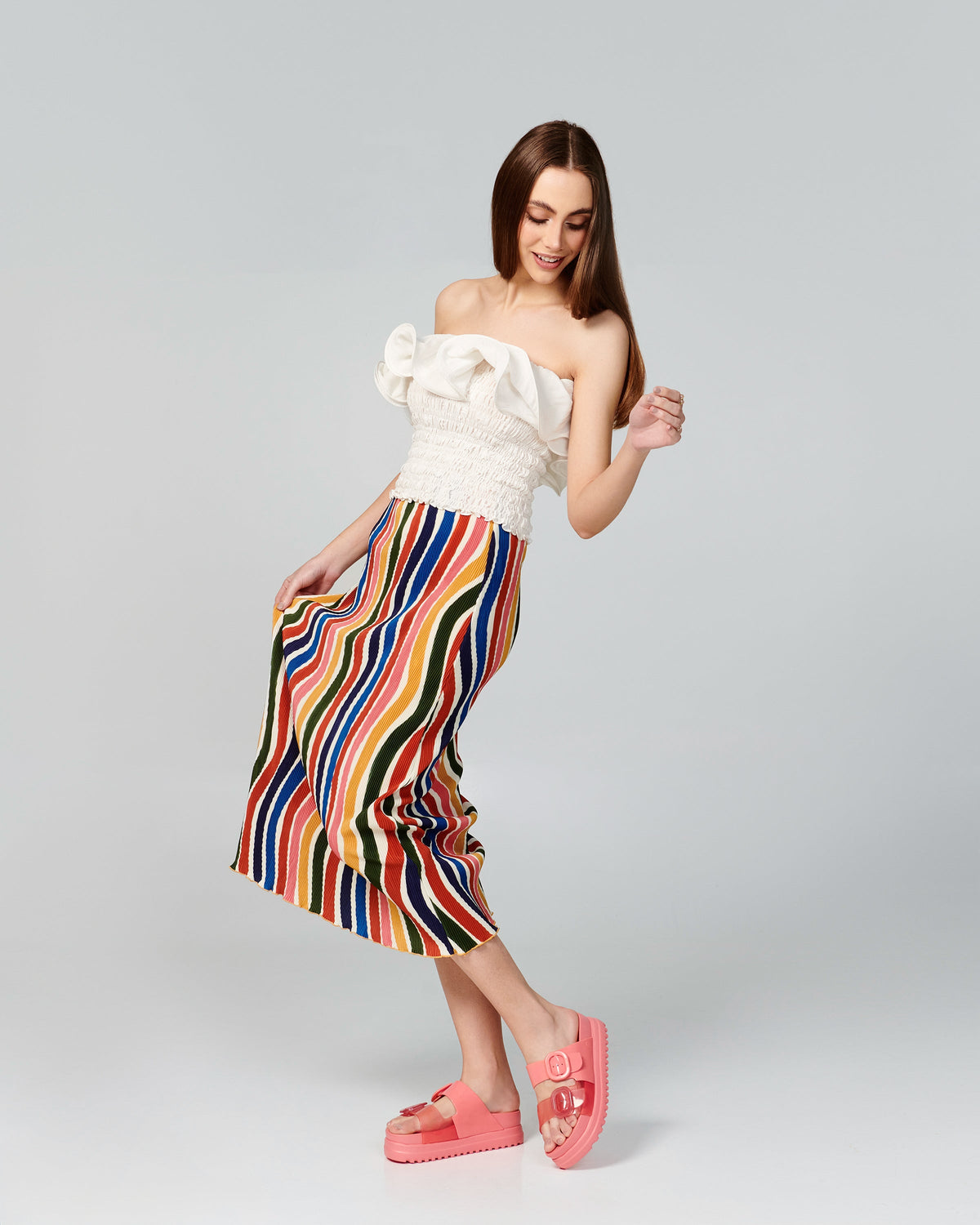 Model in a stripped skirt and white shirt wearing a pair of pink Cozy Platform slides.