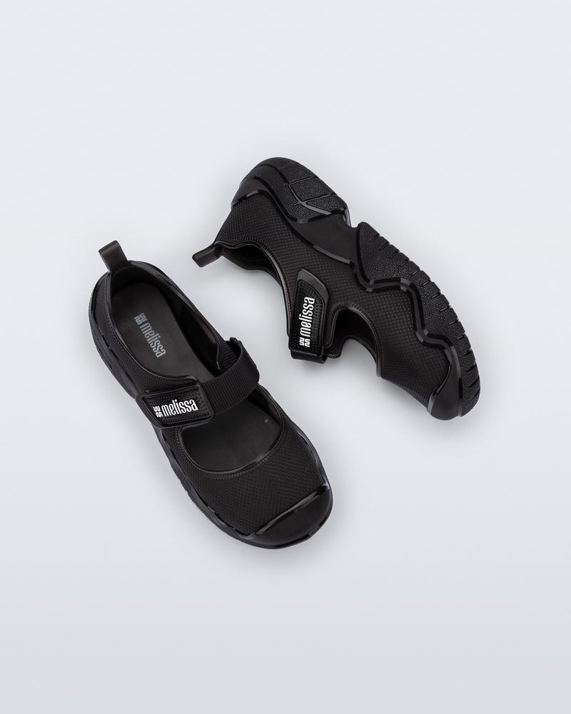 Top and side view of a pair of the Melissa Sprint Ballerina flat in black with velcro straps on a light gray background