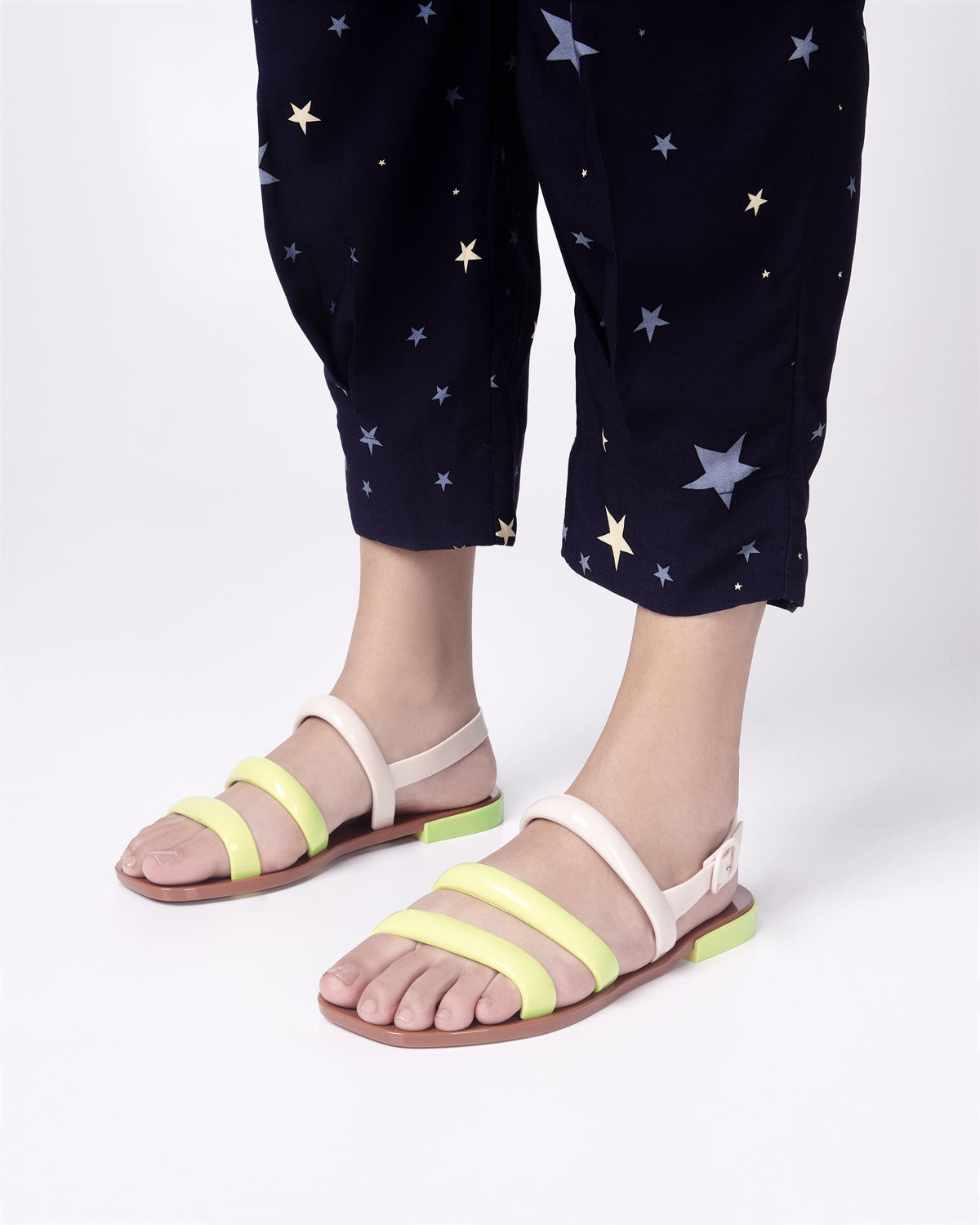 Model's legs wearing a pair of beige and yellow Essential Wave women's sandal with adjustable buckle.