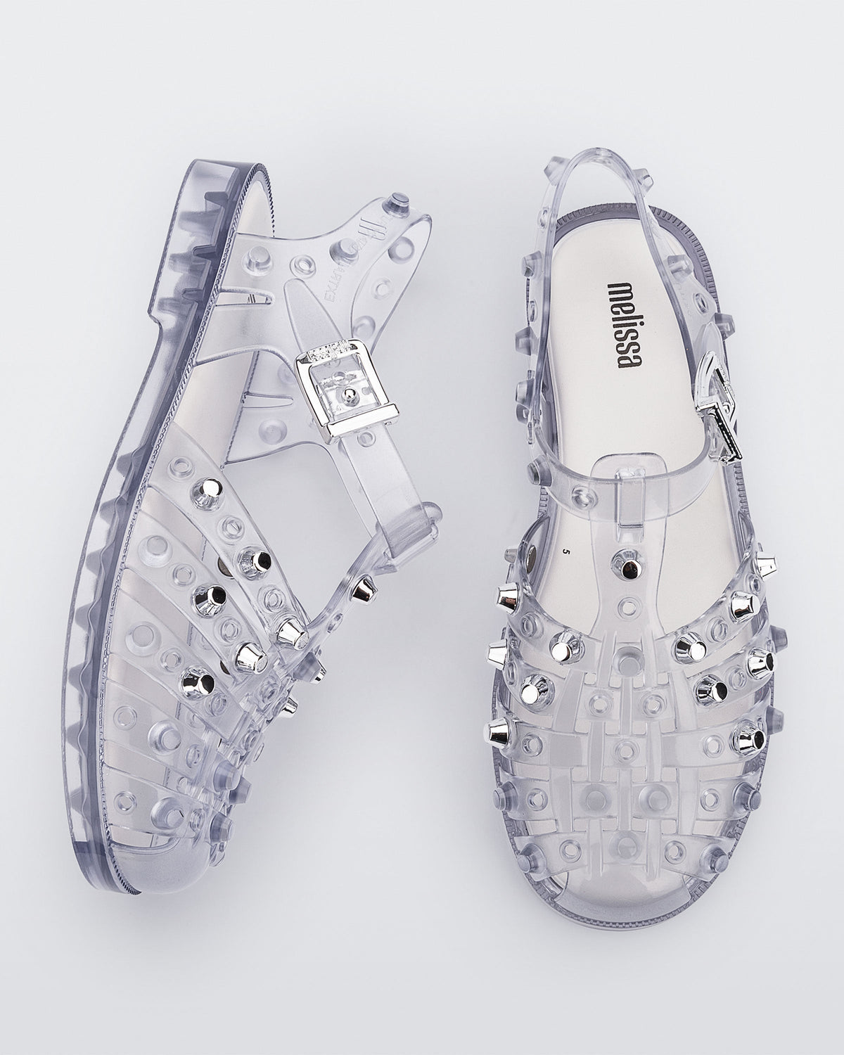 Side and top view of a pair of clear Possession Studs fisherman sandals with silver studs.