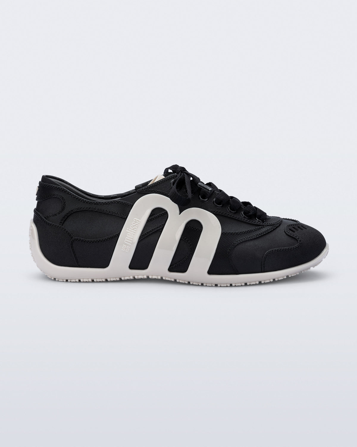 Side view of a black Motion sneaker with white colored sole and M monogram