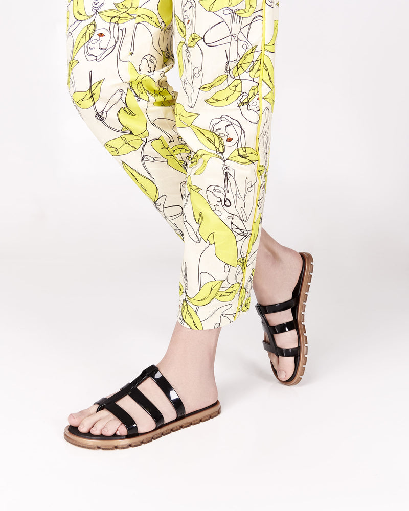 Model's legs wearing a pair of black Path adult sandals with gold sole