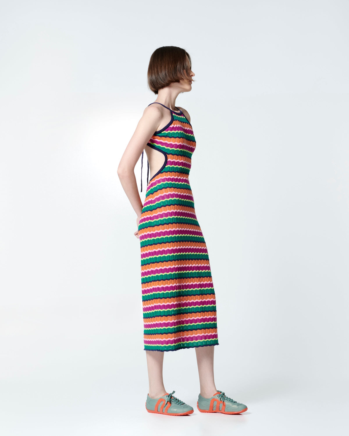 Model in multi-colored crochet dress wearing a pair of green Motion sneakers with orange colored sole and M monogram