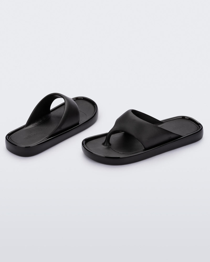 Angled view of a pair of black Float flip flops
