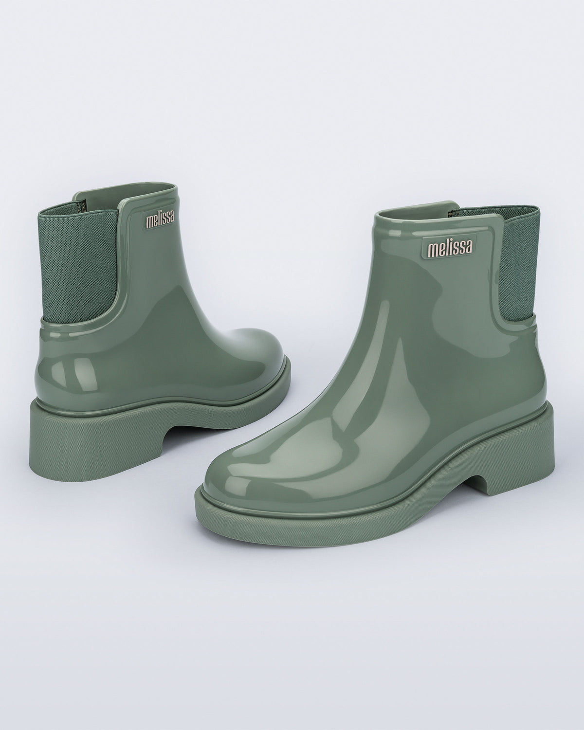 Back and angled view of a pair of sage green Chelsea Boots.