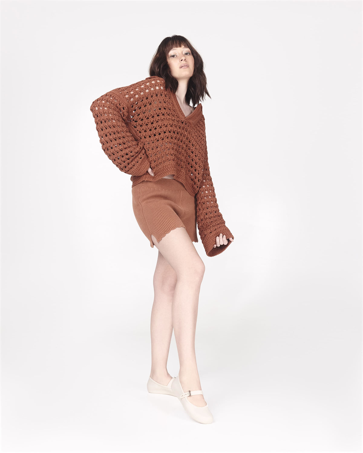 Model in a brown outfit wearing a pair of beige Soft adult flats with strap and gold buckle