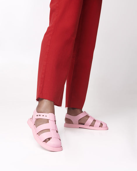 Model's legs in red pants wearing a pair of pink Emma women's sandals.