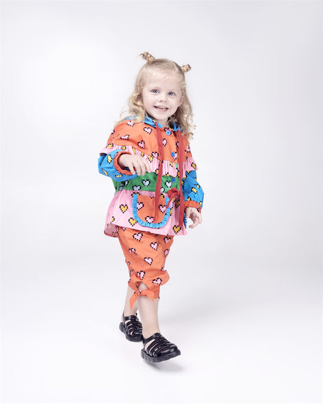 Toddler model in a mutli colored outfit wearing a pair of black Megan baby sandals.