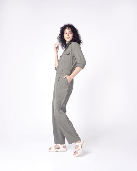 Model in a grey outfit wearing a pair of beige Free Papete sandals.