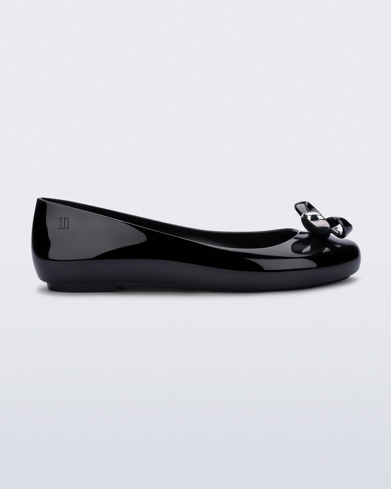 Side view of a black Sweet Love Glam ballerina flat with chrome bow