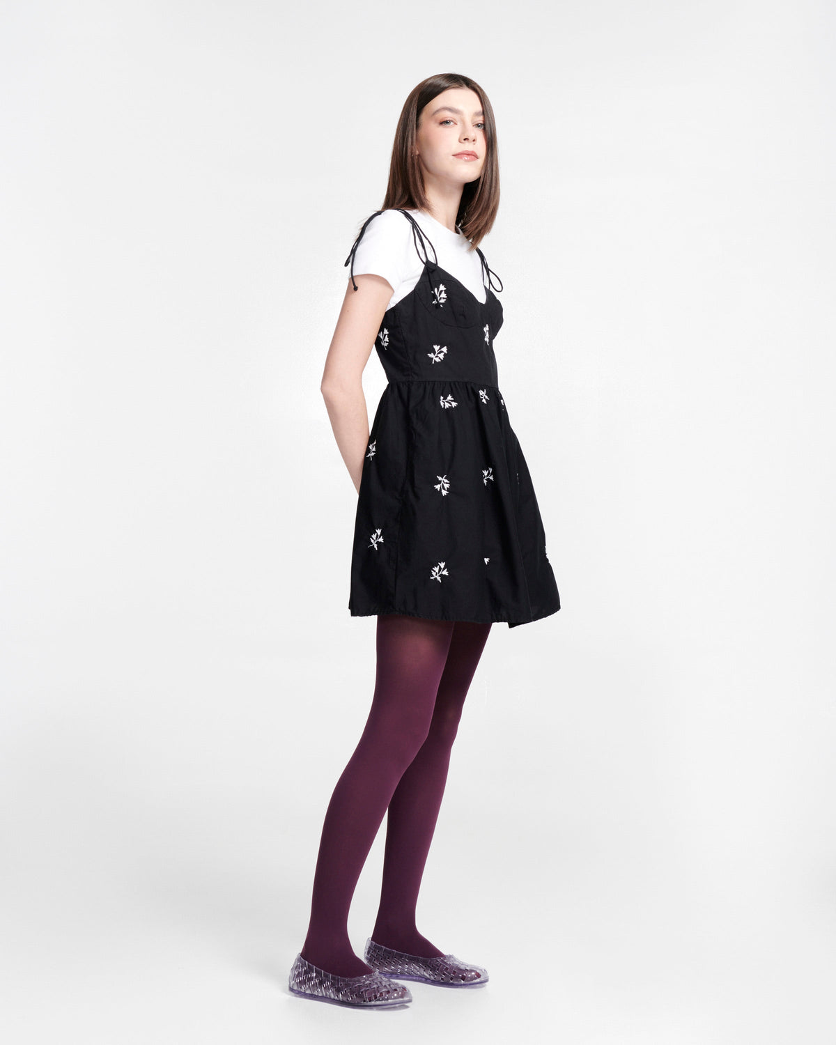 Model in black dress and purple tights wearing a pair of clear Possession Ballerina flats