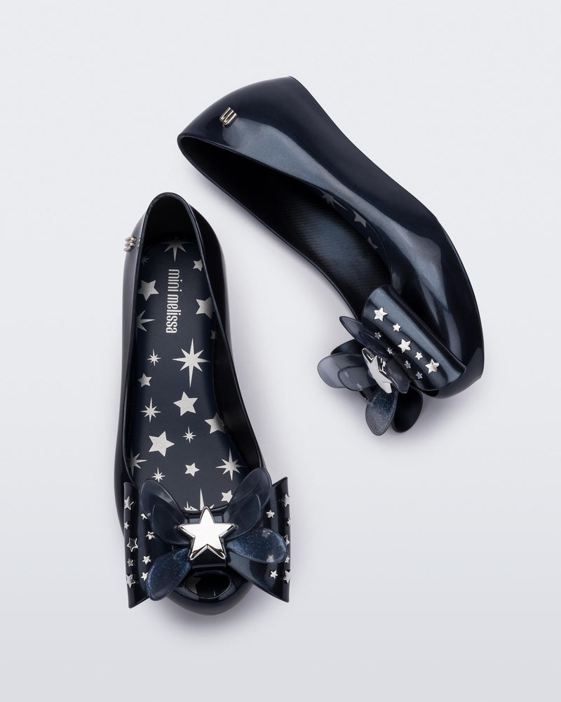 Top and side view of a pair of Mini Melissa Ultragirl peeptoe ballet flats in blue with star printed butterfly bow applique.