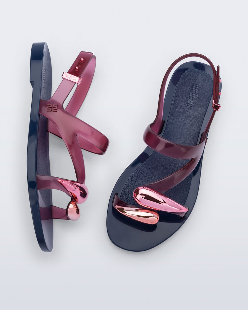 Top and side view of a pair of pink Iris sandals with blue sole and rose gold upper embellishments